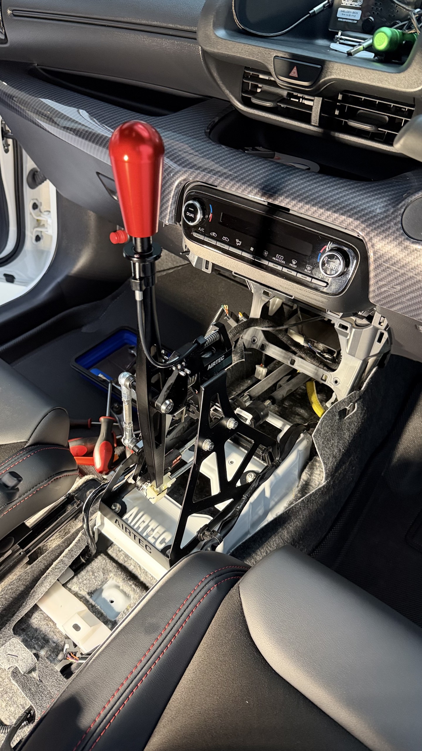 ชุดเกียร์ AIRTEC Short Shifter วางลงบนจุดยึดเดิมของ Toyota GR Yaris Gen 1 พร้อมหัวเกียร์สีแดง