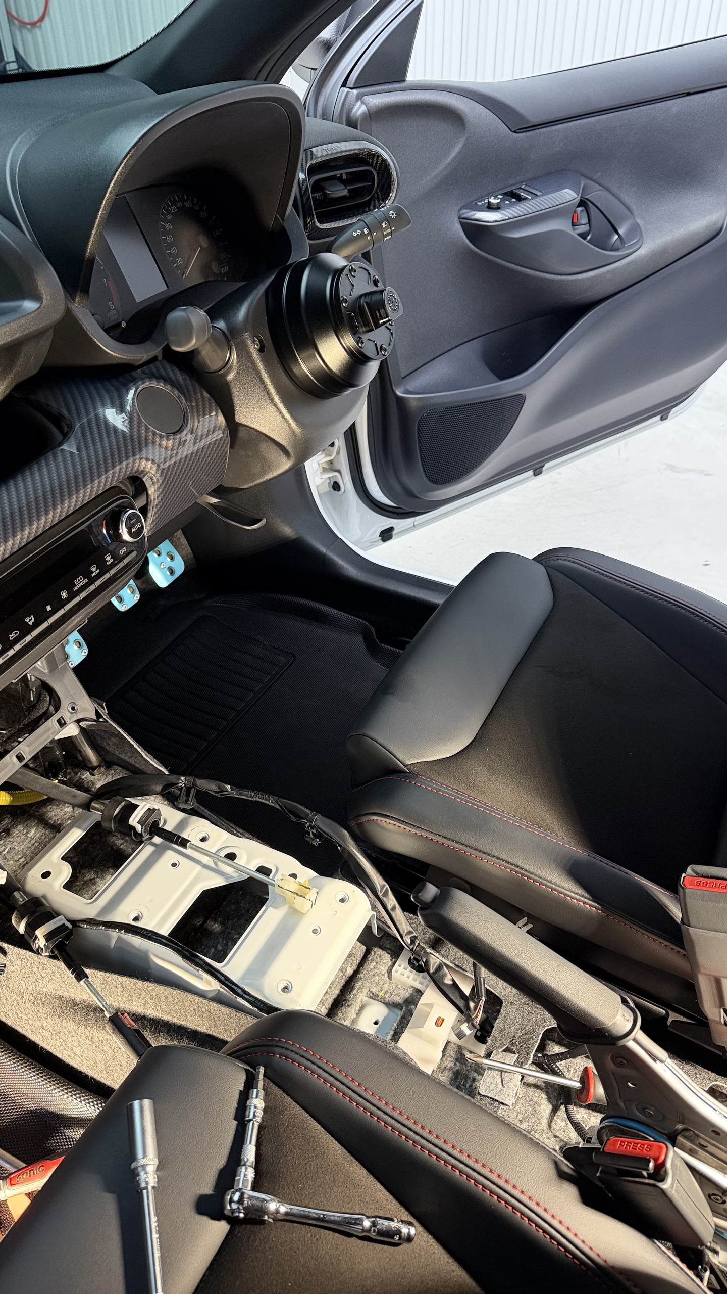 พื้นที่ใต้คอนโซลกลางของ GR Yaris Gen 1 หลังถอดชุดเกียร์เดิมออก เห็นแชสซีและสายเกียร์เดิม