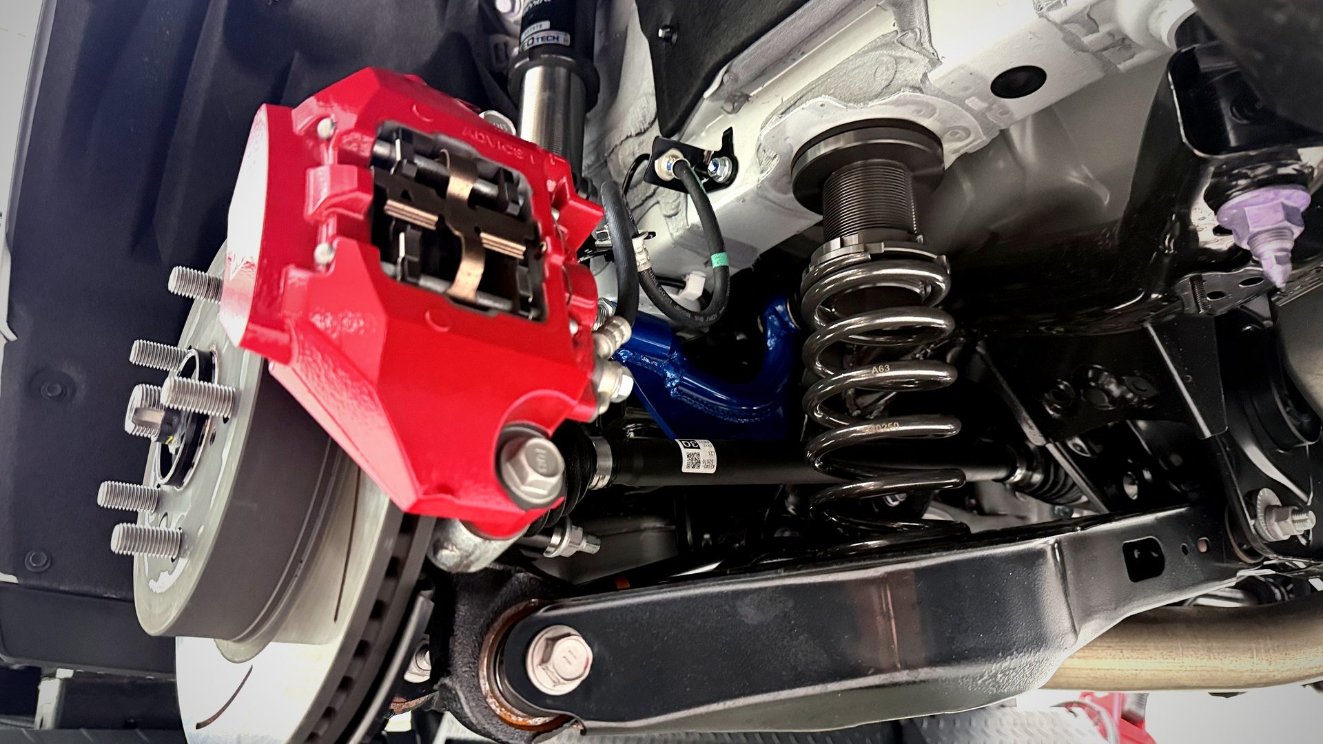 Cusco rear camber arm สีน้ำเงิน + NeoTech coilover หลัง GR Yaris — มุมมองจากใต้รถ
