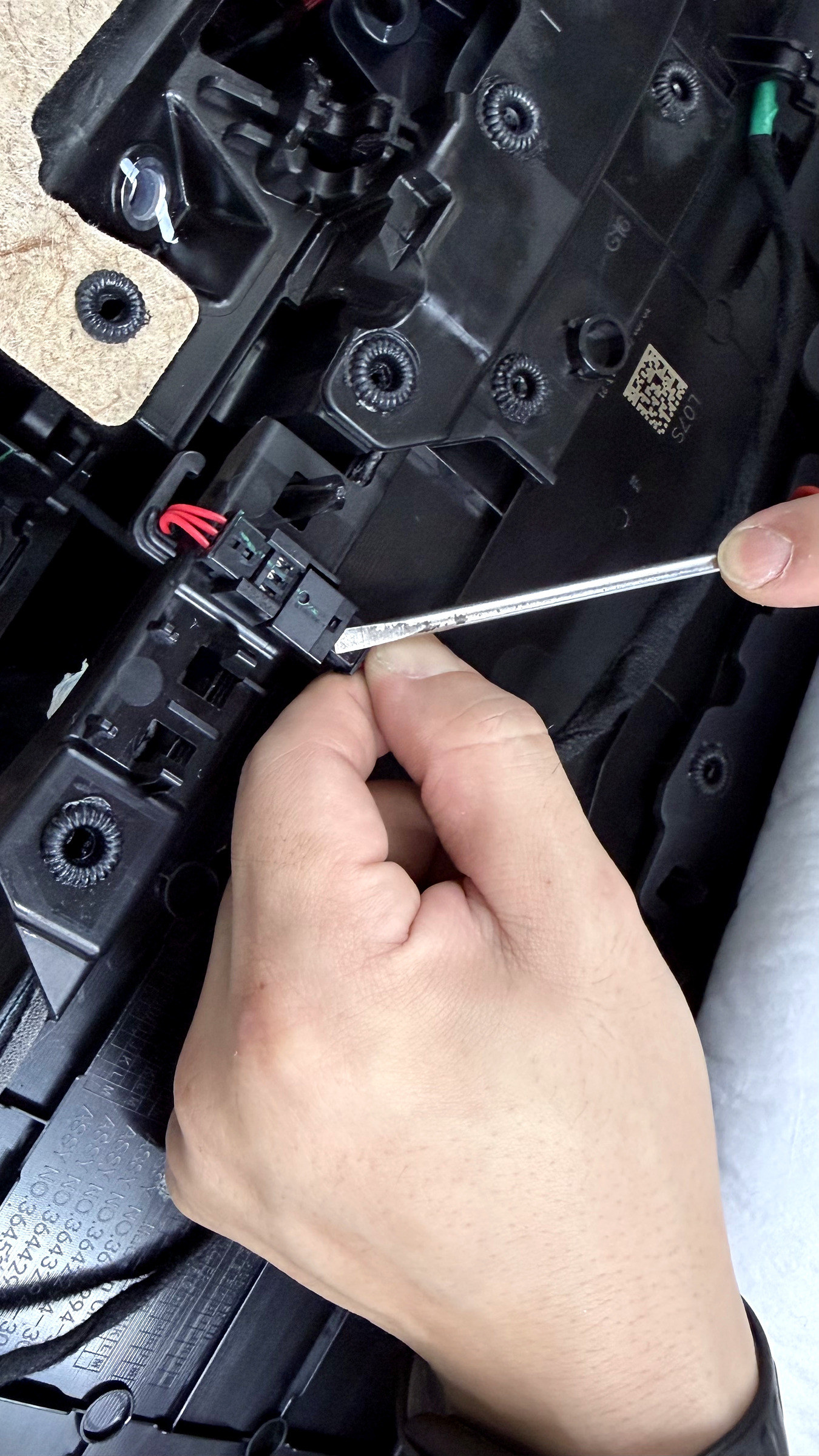 ใช้ไขควงปากแบนเล็กค่อย ๆ เขี่ยเขี้ยวล็อคของขั้วต่อประตู Tesla ก่อนถอด ที่ G-FORCE